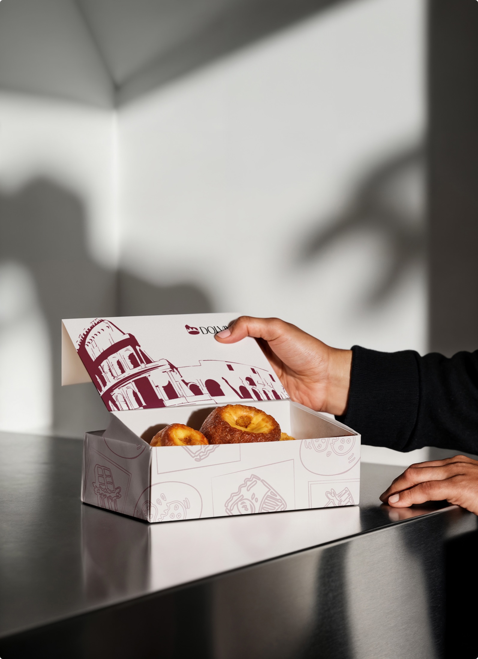 Open Dolvivo pastry box with baked pastries held above a table
